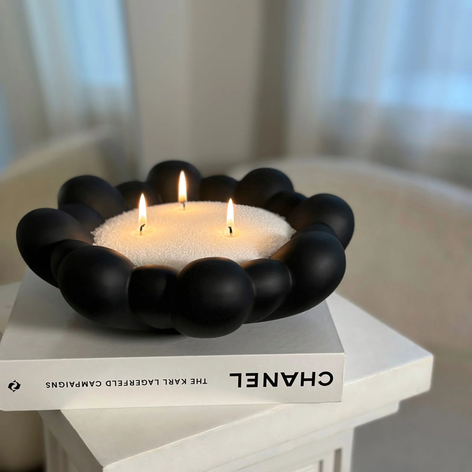 Sort perlebesat lysestage med tre lys på en bog